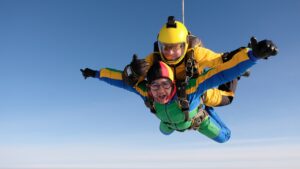 Tandem skydiving instructor and participant freefalling through a clear blue sky during an exciting first time skydive experience.